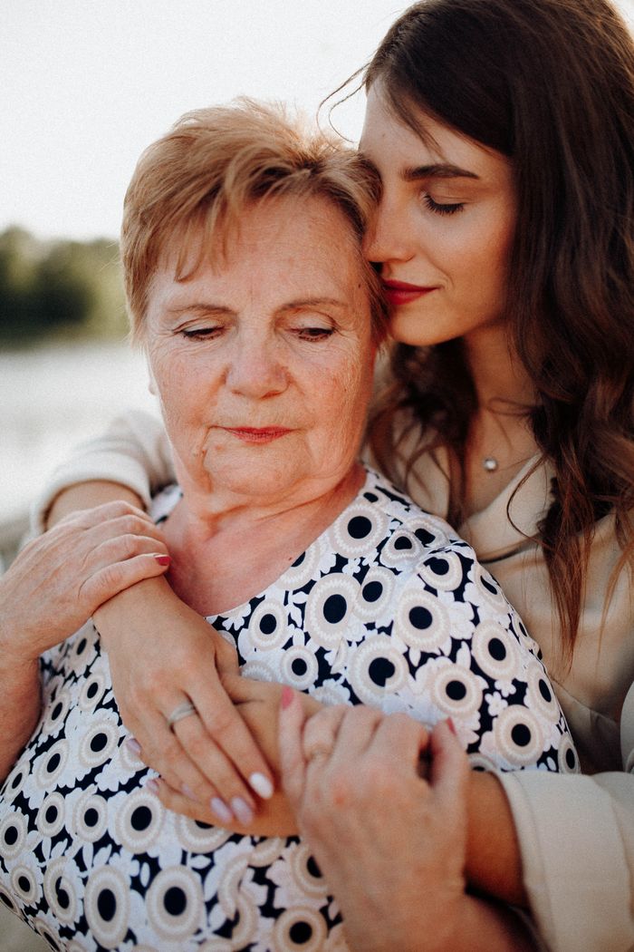 Elderly mother and young daughter embracing in a warm, loving moment.